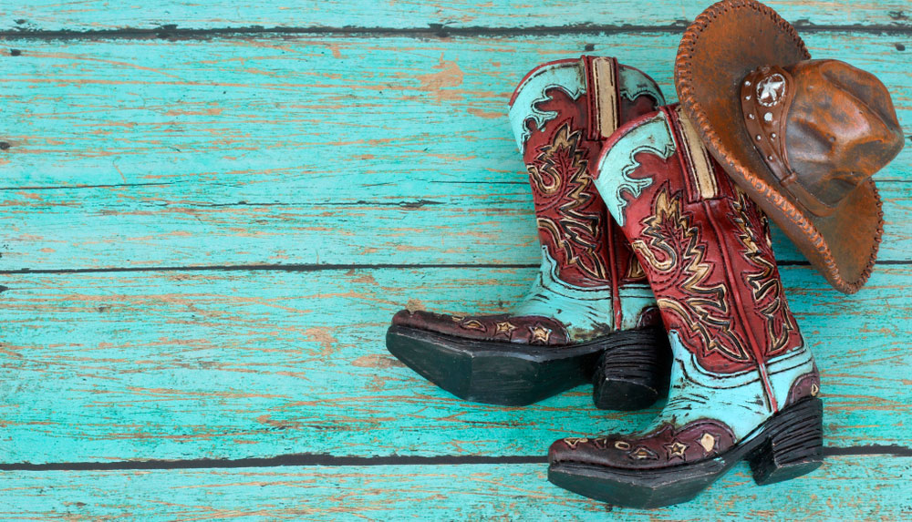 cowboy boots and hat on teal wood