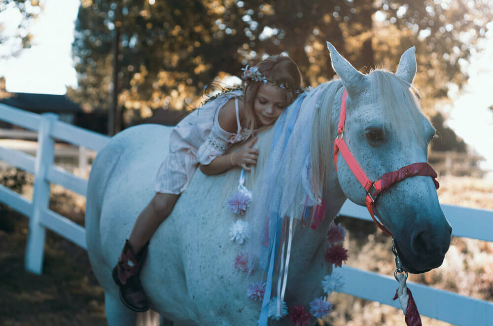 little girl is resting on the horse back