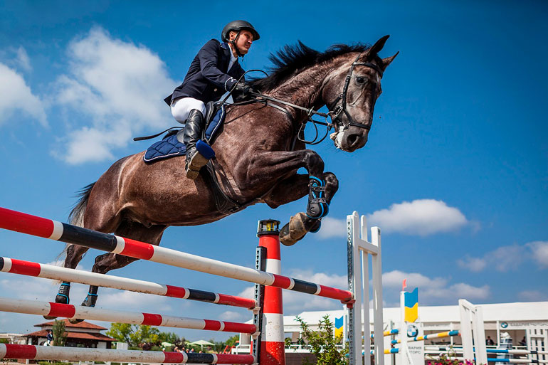 man is jumping over obstacle with horse