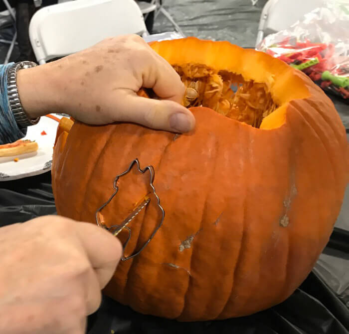 man is using pumpkin carving knife