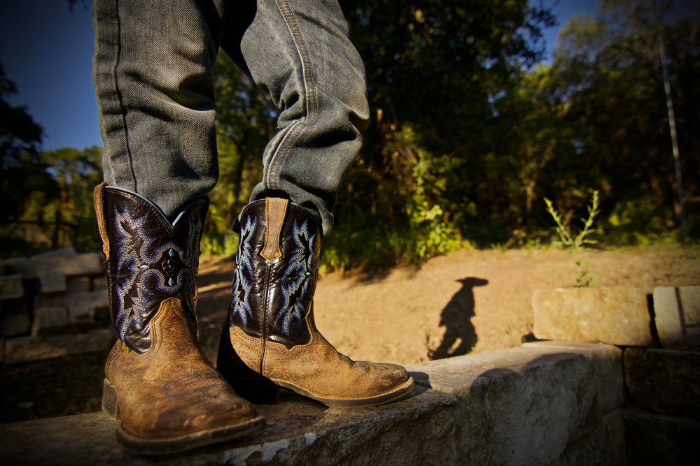 man standing in cowboy boots with stitching