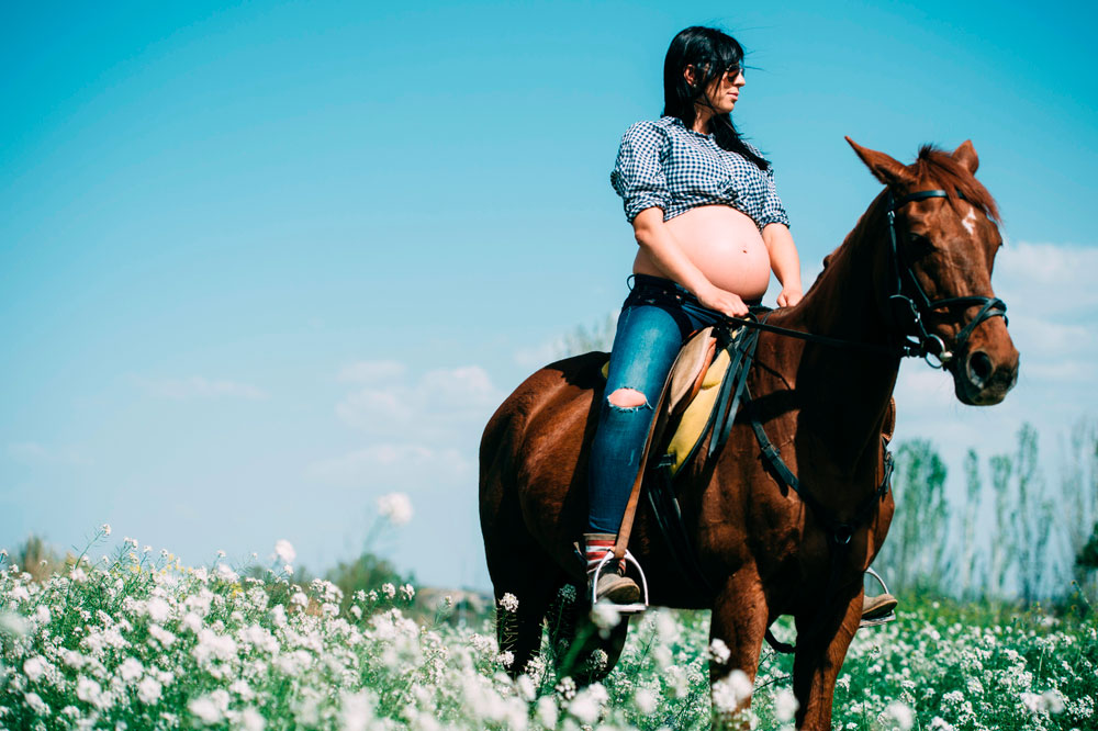 pregnant woman in shirt riding horse