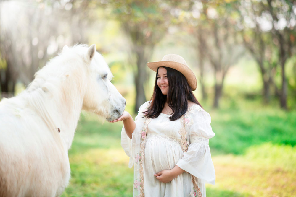 pregnant woman petting white horse