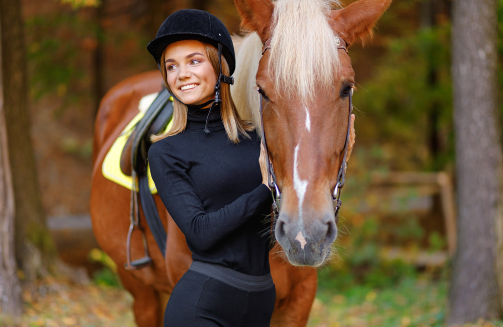 woman is posing near the chestnut horse