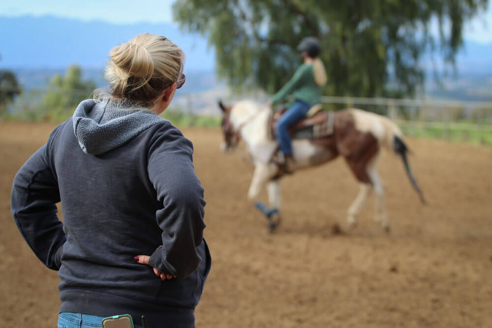 woman is teaching a horseback riding